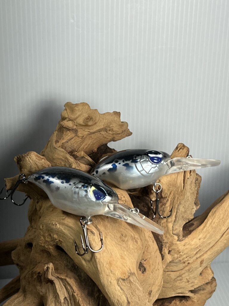 Pair of silver and blue painted crankbaits on driftwood